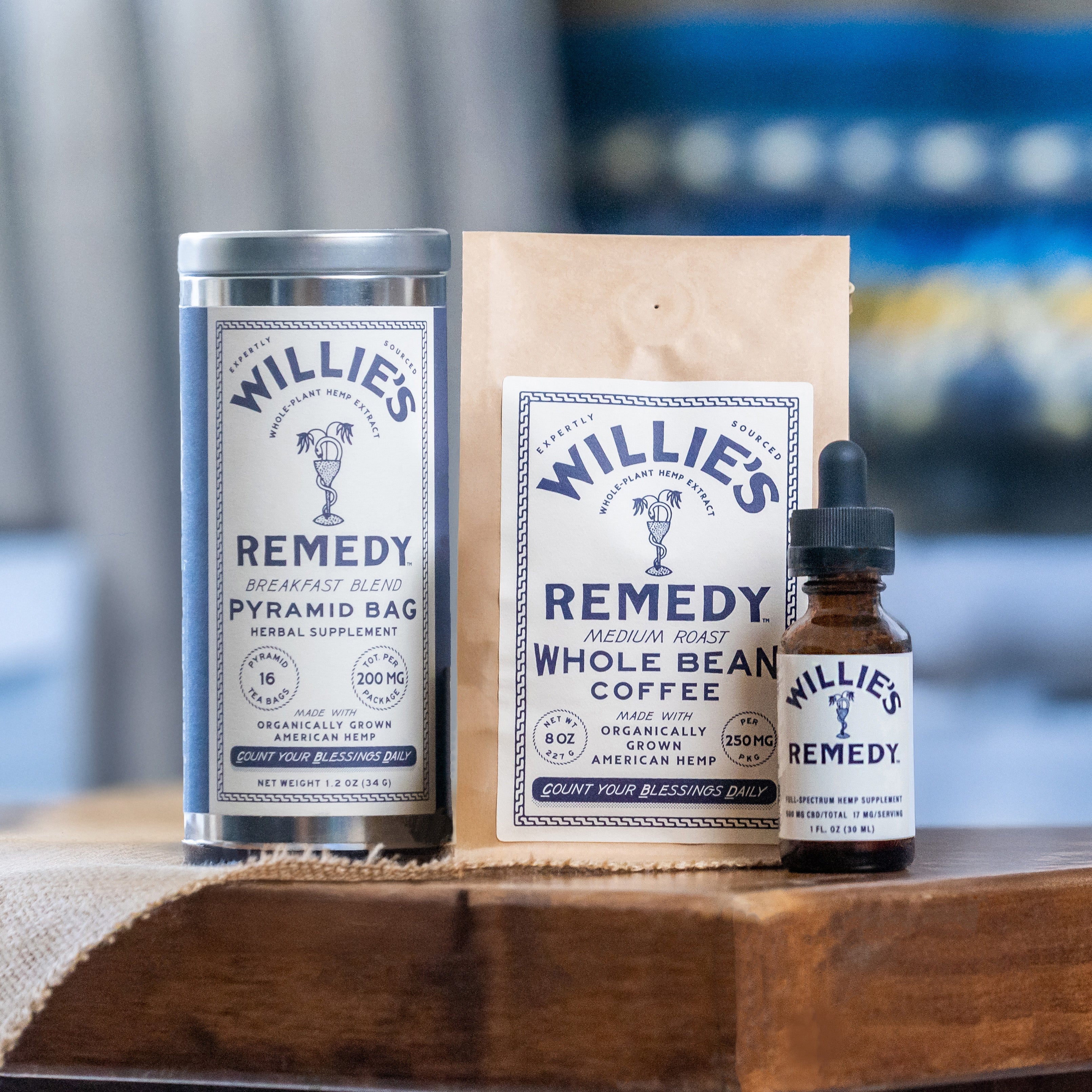 Willie's Remedy coffee products including a canister, package, and dropper bottle on a wooden surface.