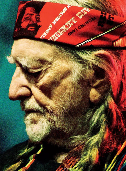 Close-up of Willie Nelson wearing a red bandana with text and graphics, against a blue background.