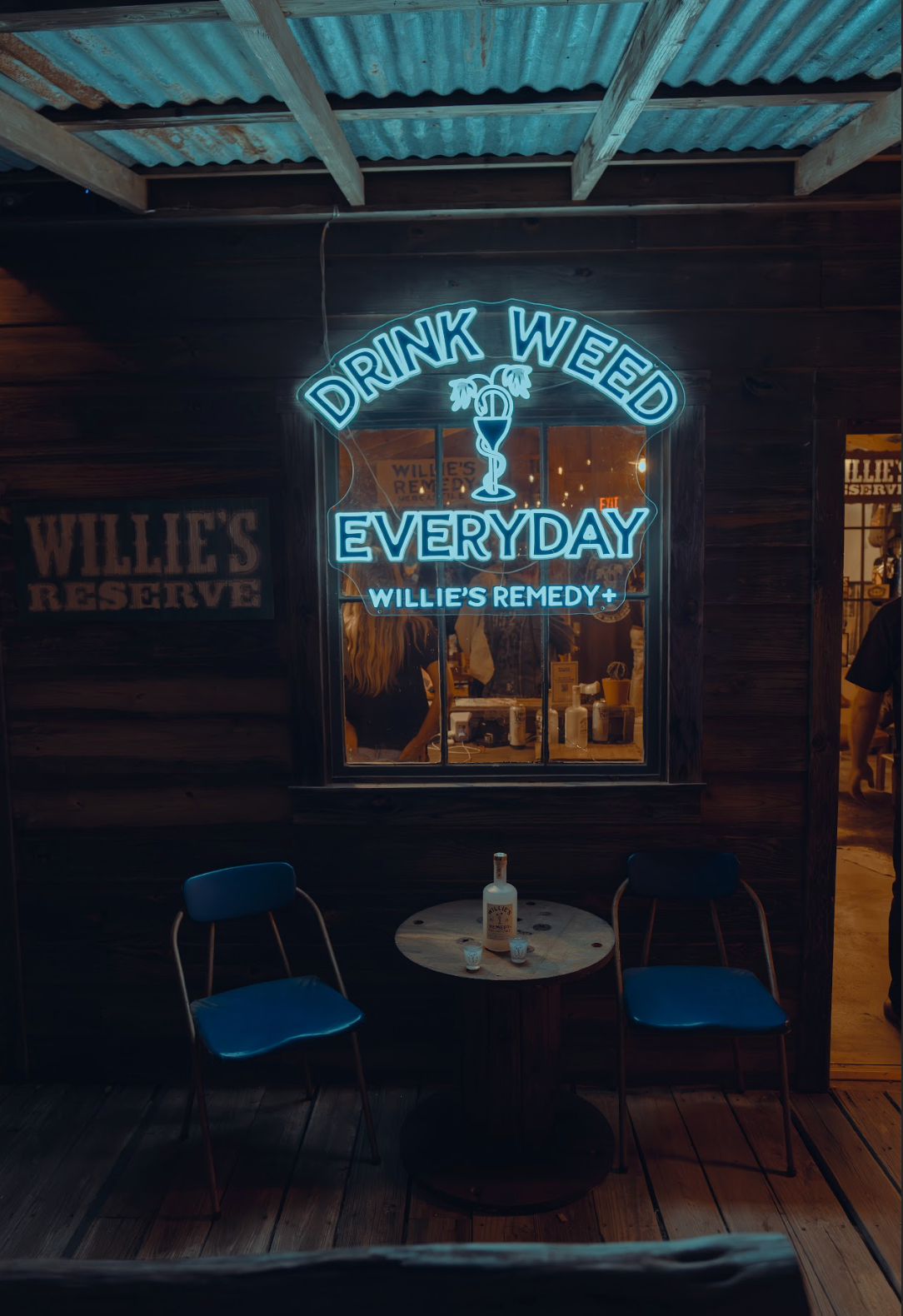 Neon sign in a bar with 'Drink Weed Everyday' and 'Willie's Remedy' branding.